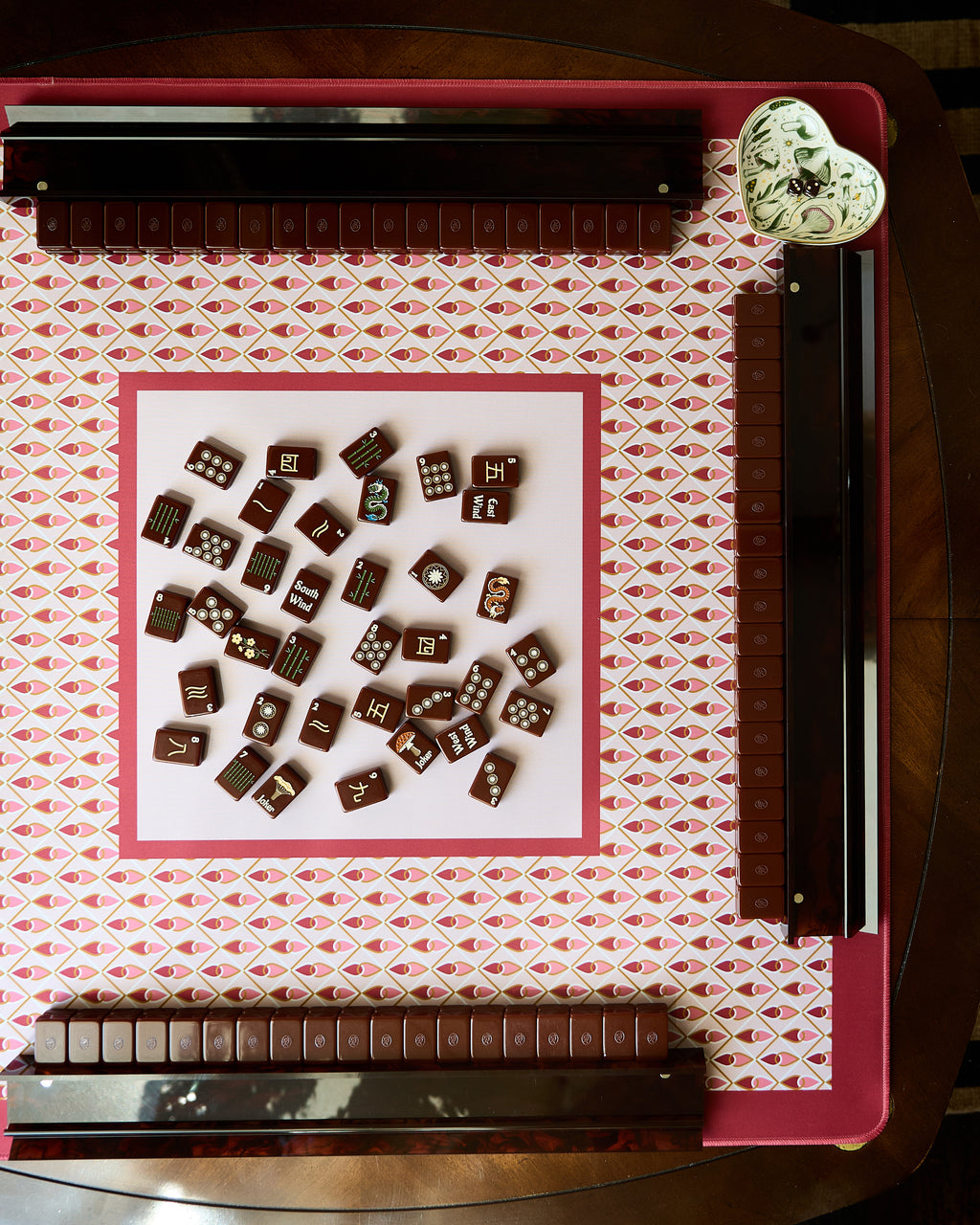 Currant mahjong mat on a mahjong table with tiles and racks, seen from above