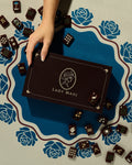 Hand holding a Lady Mahj mahjong tile box with dark mahjong tiles on a blue rose mahjong mat